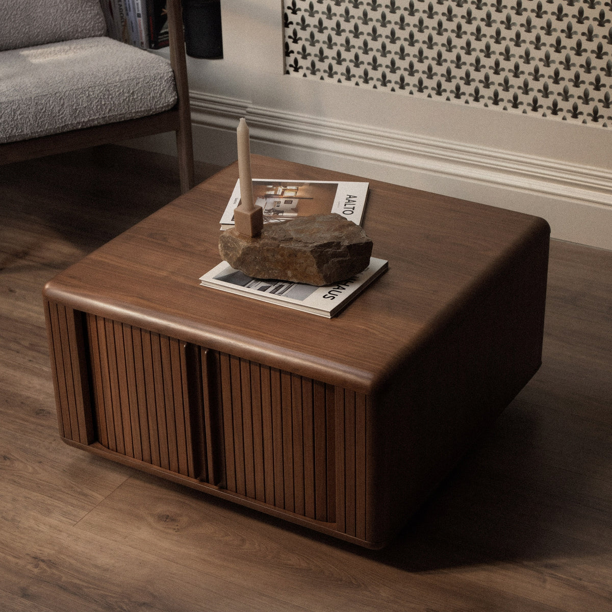 A mid-century modern wooden coffee table with a warm brown finish, featuring vertical slatted front doors and a rounded top.