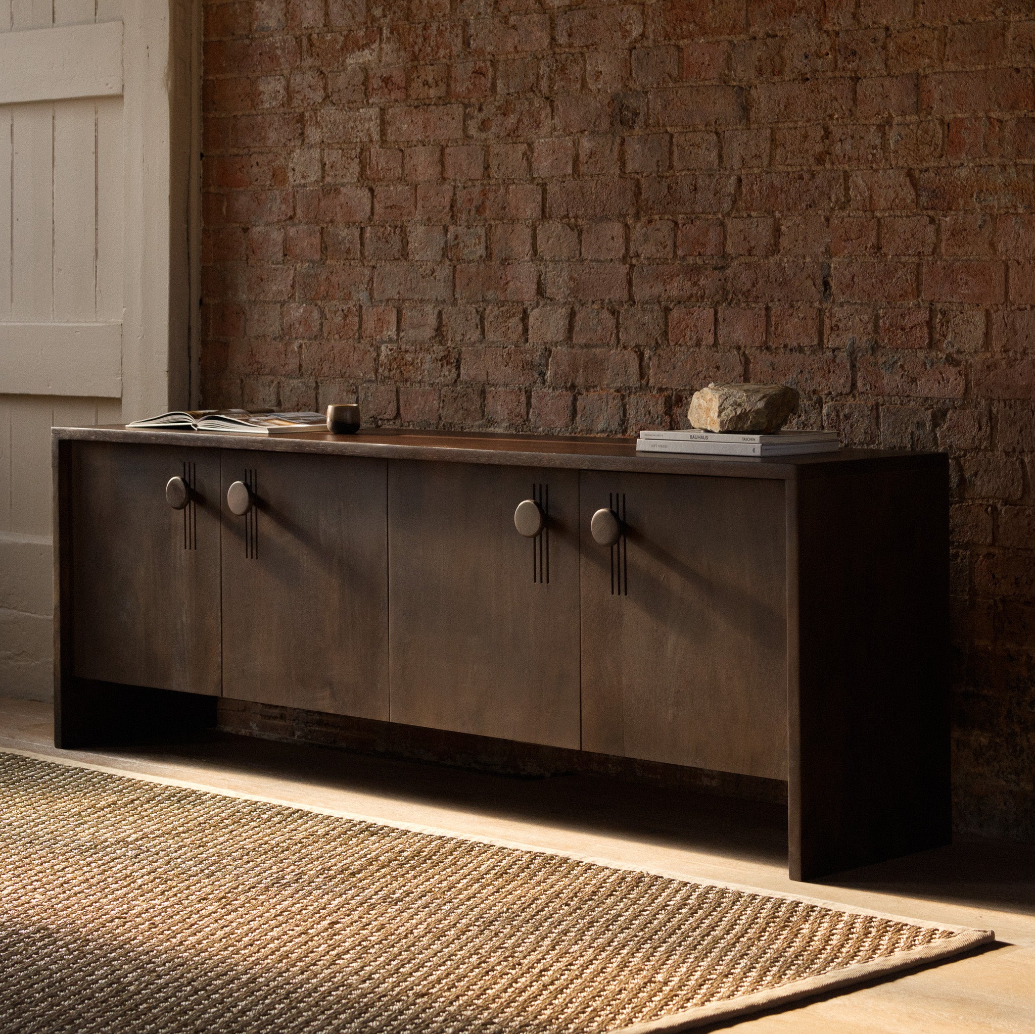 Dark wood sideboard against a brick wall
