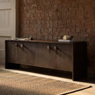 Dark wood sideboard against a brick wall