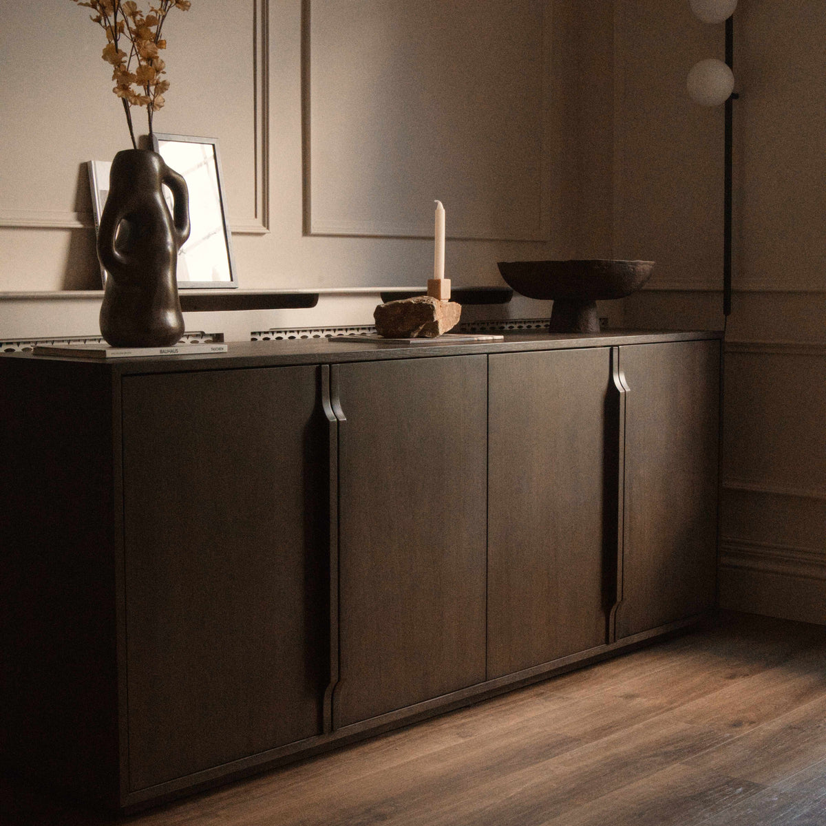 A modern four-door sideboard cabinet in dark brown wood with slim vertical handles.
