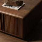 A mid-century modern wooden coffee table with a warm brown finish, featuring vertical slatted front doors and a rounded top.
